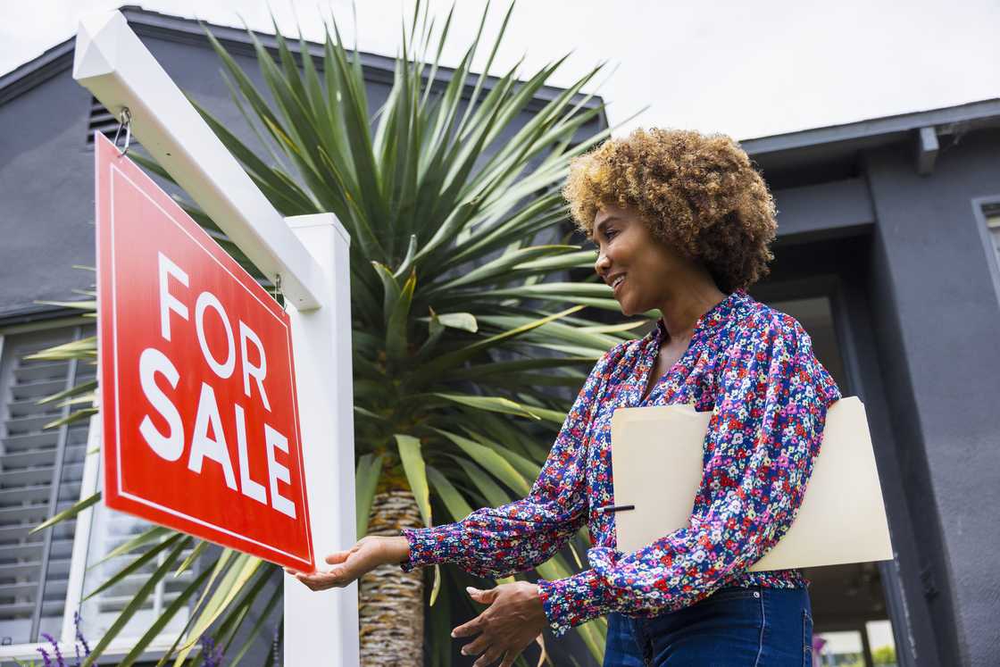 Real estate agent adjusting for sale sign in front of home.