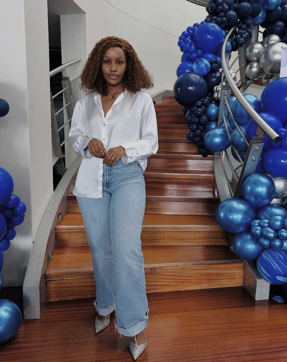 A South African woman posed in a picture while dressed in a white shirt and blue jeans.