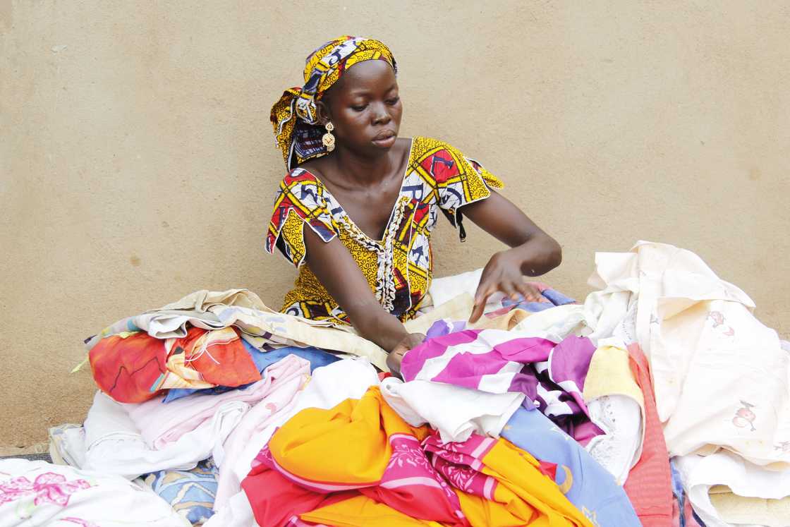 A young woman selling second-hand clothes at a market.
