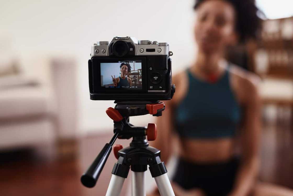 A young woman recording herself doing yoga at home