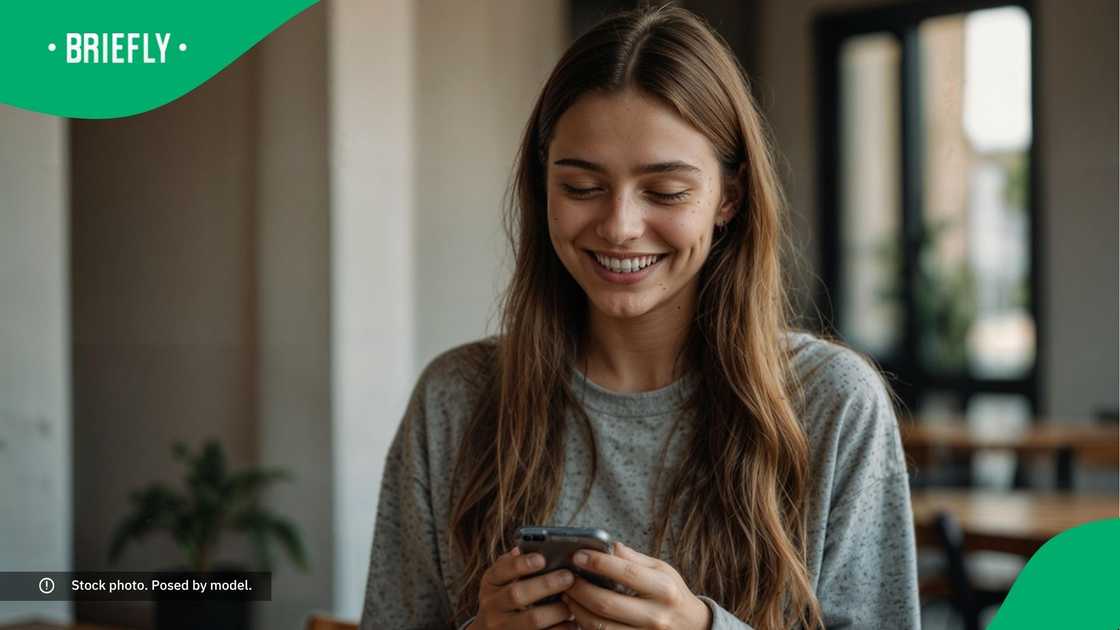 A woman smiling at her phone. A woman smiling at her phone.