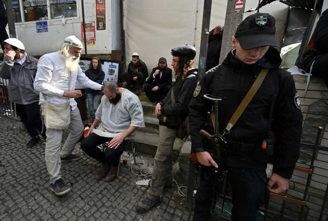 An armed policeman stands guard as Hasidic Jewish pilgrims have their hair cut after praying at the tomb of Rabbi Nachman to mark the Jewish new year An armed policeman stands guard as Hasidic Jewish pilgrims have their hair cut after praying at the tomb of Rabbi Nachman to mark the Jewish new year