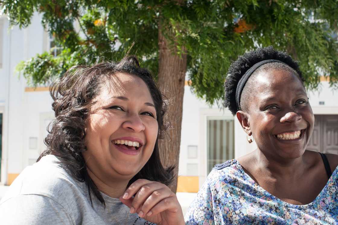 Women sit under a jacaranda tree during a stokvel meeting.