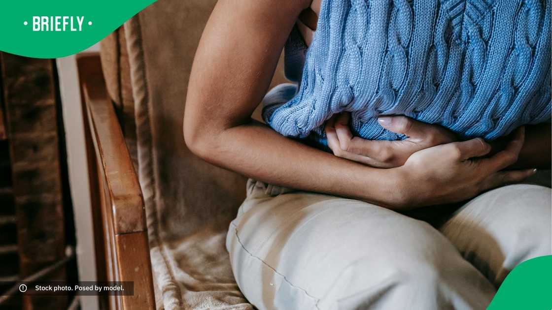 A woman holding her stomach. A woman holding her stomach.
