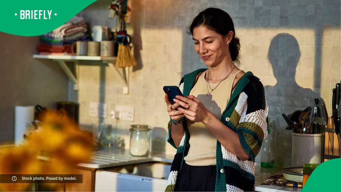 A woman smiling at her phone.