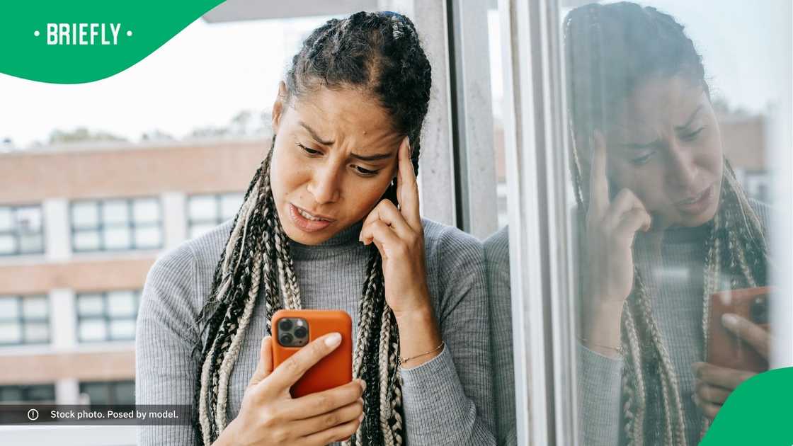 A sad woman looking at her phone.