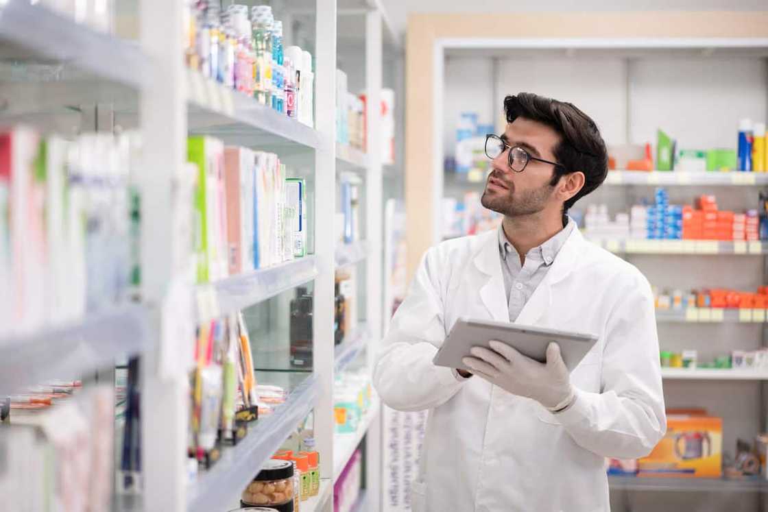 A pharmacist using a digital tablet to do inventory in a pharmacy A pharmacist using a digital tablet to do inventory in a pharmacy