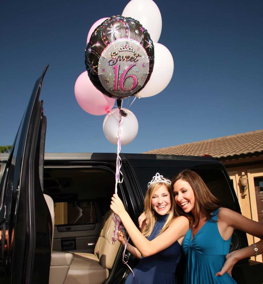 two teenage girls with balloons beside a car two teenage girls with balloons beside a car