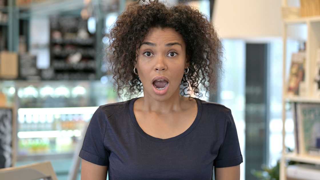 A woman with a shocked face inside a restaurant. A woman with a shocked face inside a restaurant.