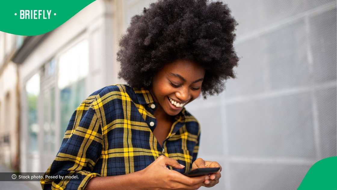 A woman smiling at her phone.