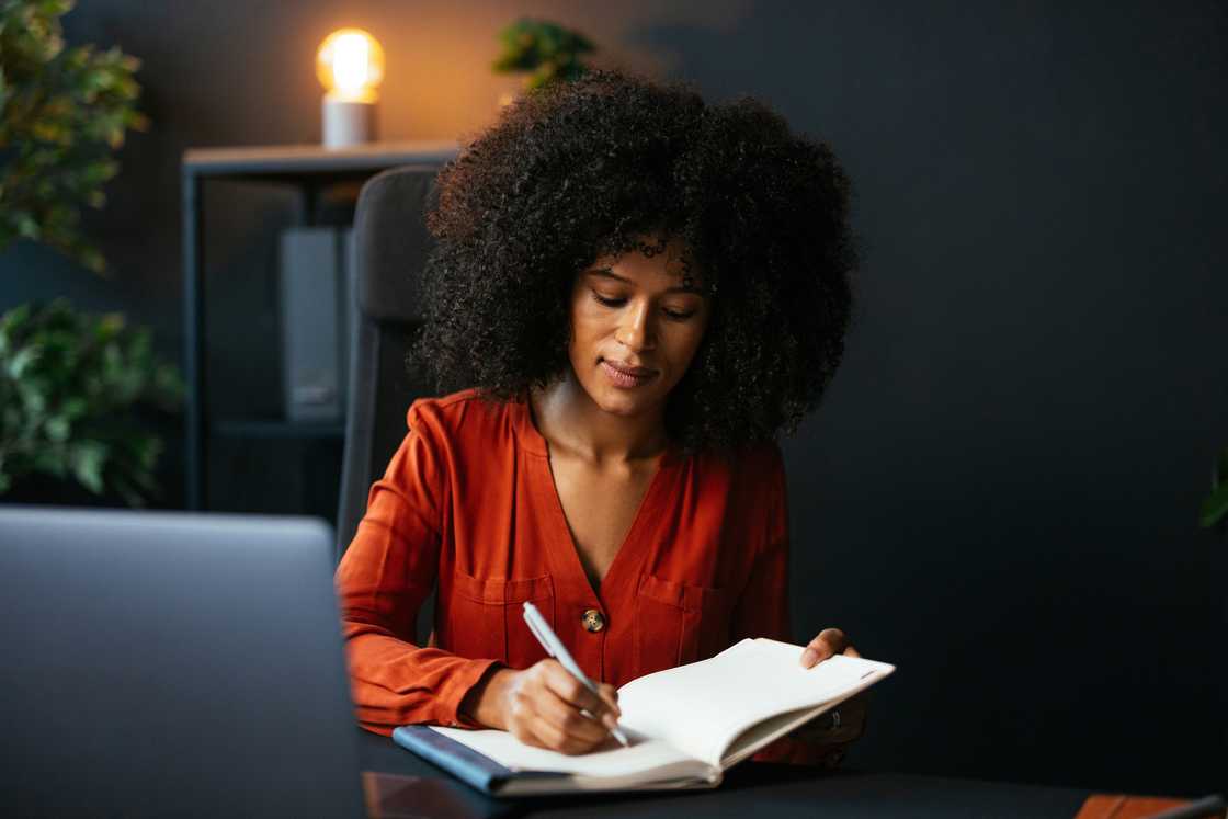 A woman writing on her journal at night. A woman writing on her journal at night.