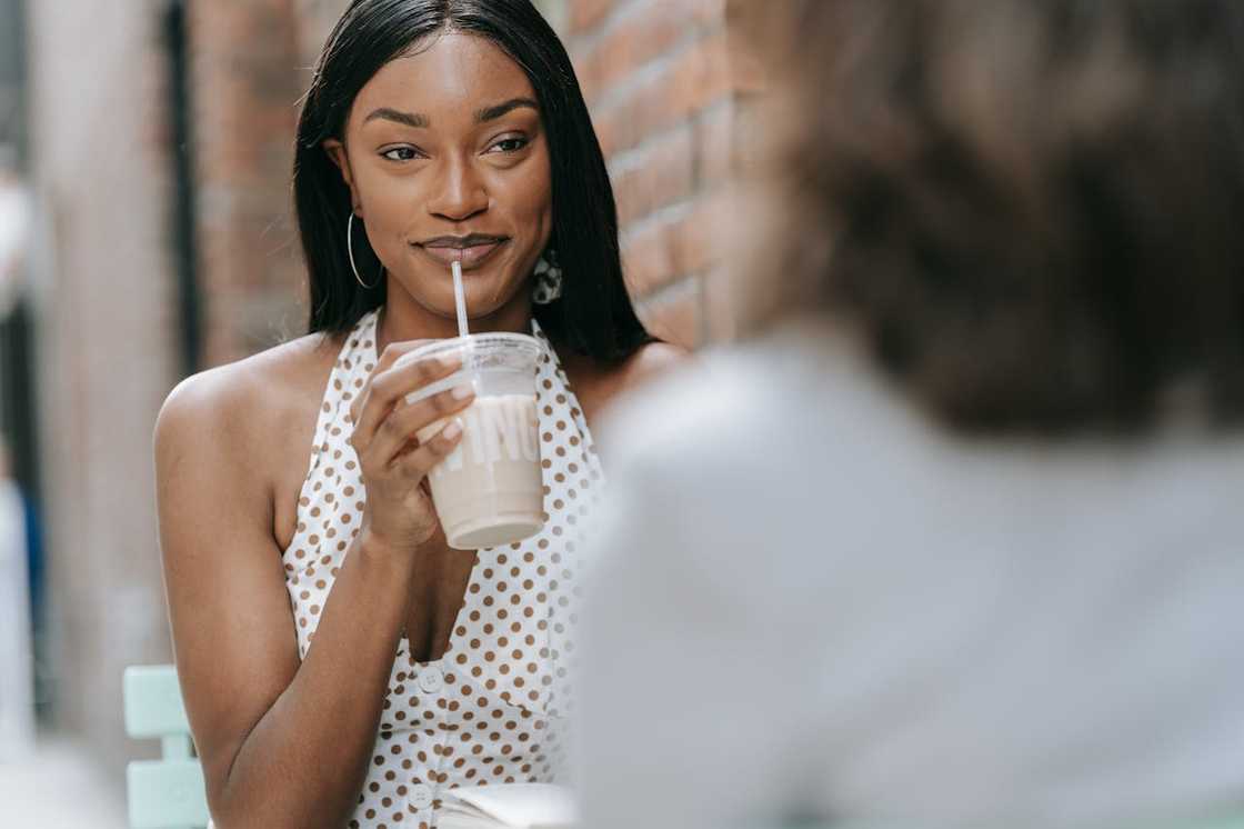 A woman takes a sip of a drink at a casual outing.