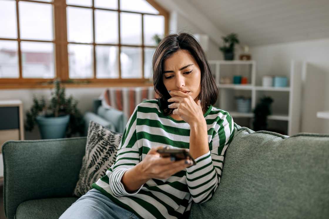 A confused woman looking at her phone.