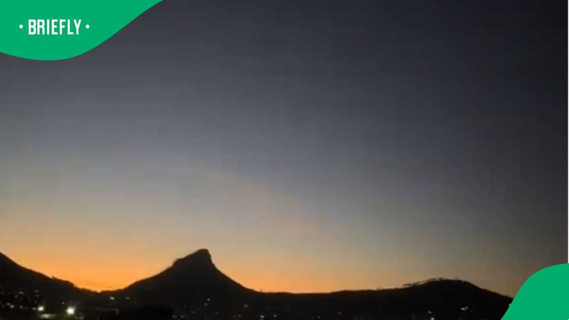 A scenic view of Cape Town at dusk with Lion’s Head silhouetted against a glowing orange horizon and a darkening sky above. A scenic view of Cape Town at dusk with Lion’s Head silhouetted against a glowing orange horizon and a darkening sky above.