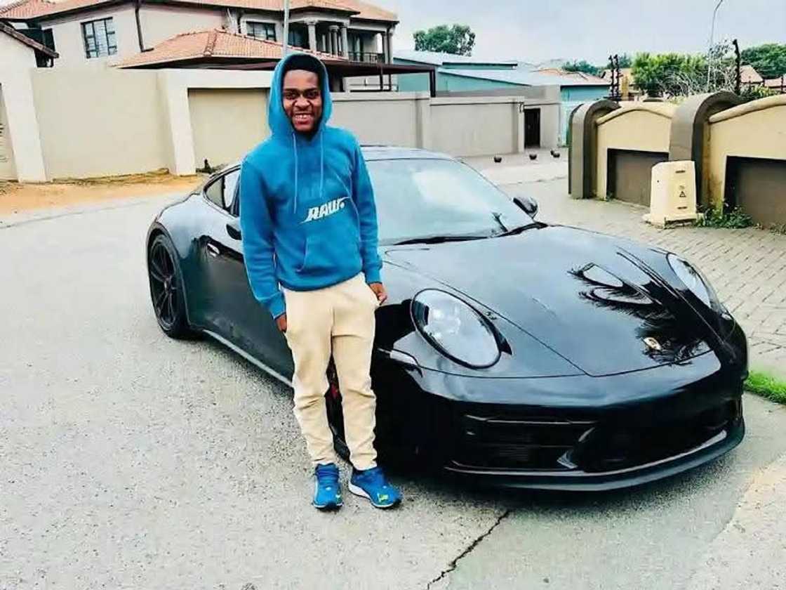 Mfundo Vilakazi strikes a confident pose beside a sleek Porsche.