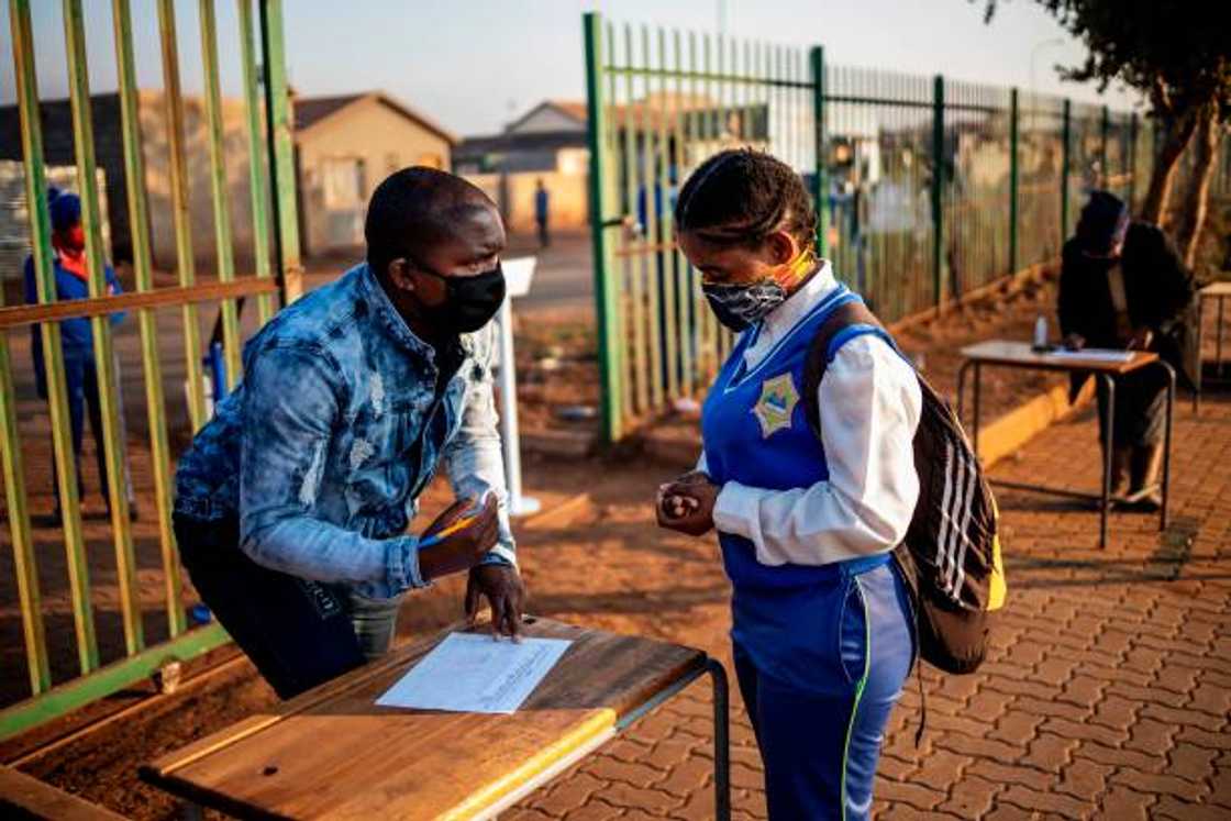 A teacher at the Winnie Mandela Secondary School screening a pupil before admitting her into the school.