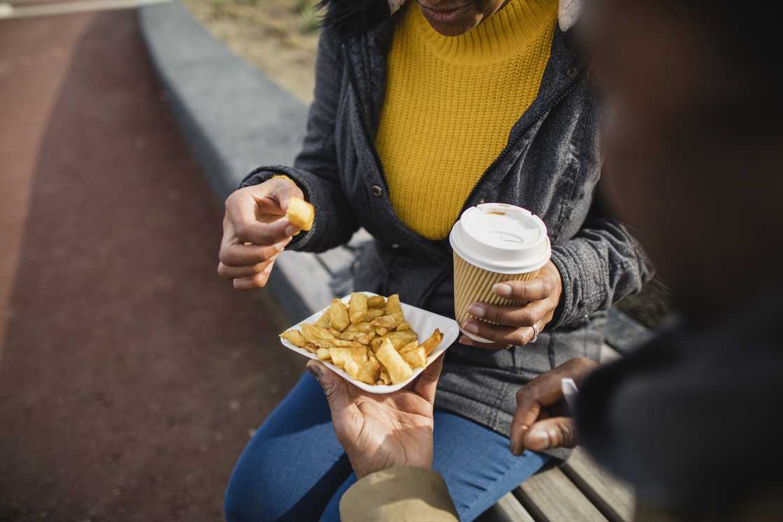 A lady sharing food with a man in the streets