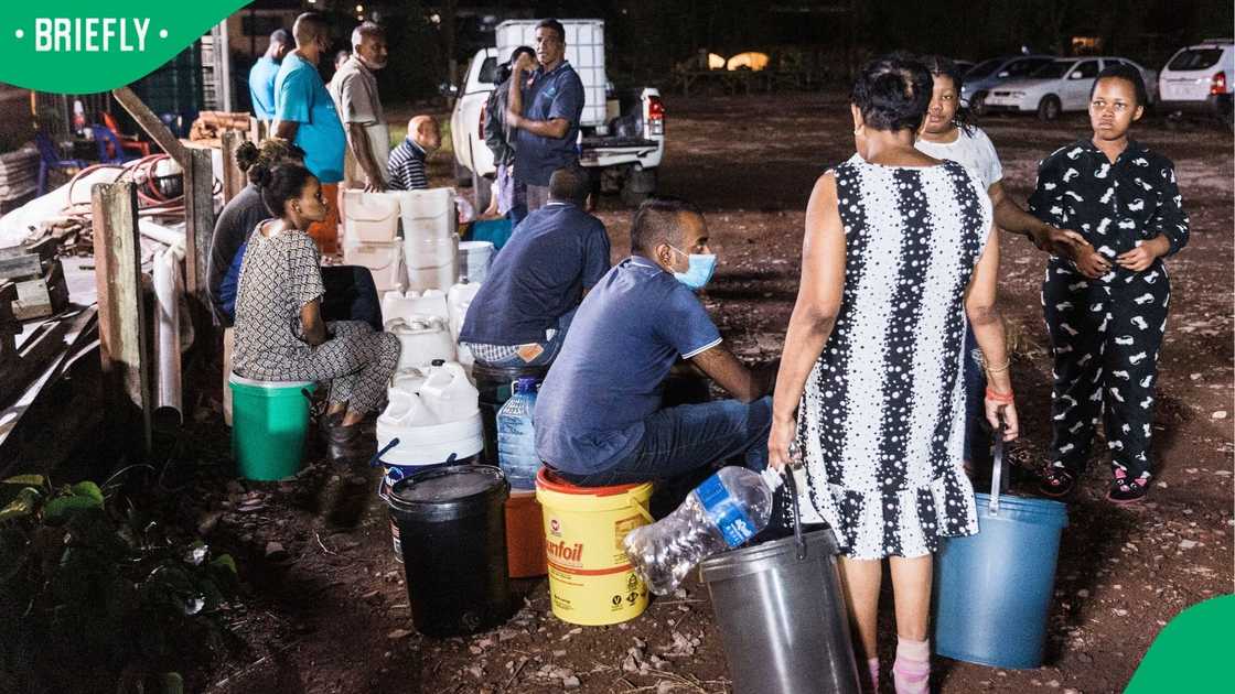 Members of the public stand in a queue waiting for a water tanker to deliver water