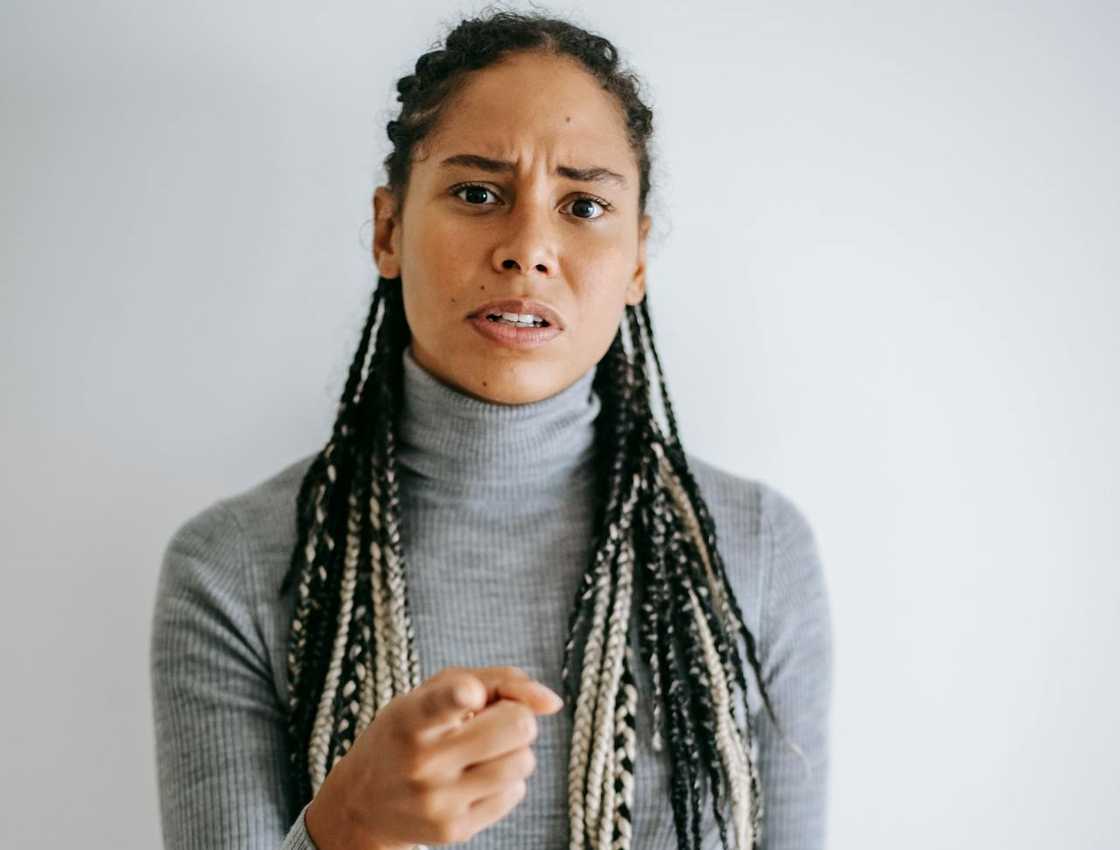 A woman points forward with a tense, accusing expression. A woman points forward with a tense, accusing expression.