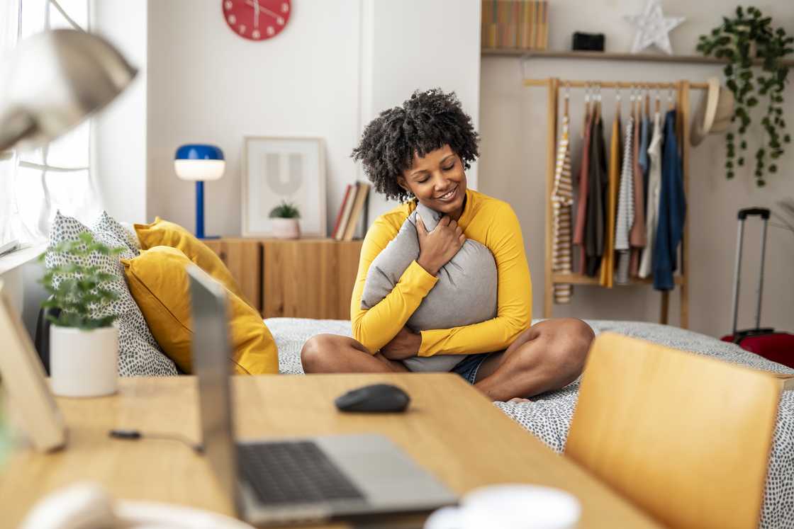 A woman embraces a pillow in her apartment. A woman embraces a pillow in her apartment.