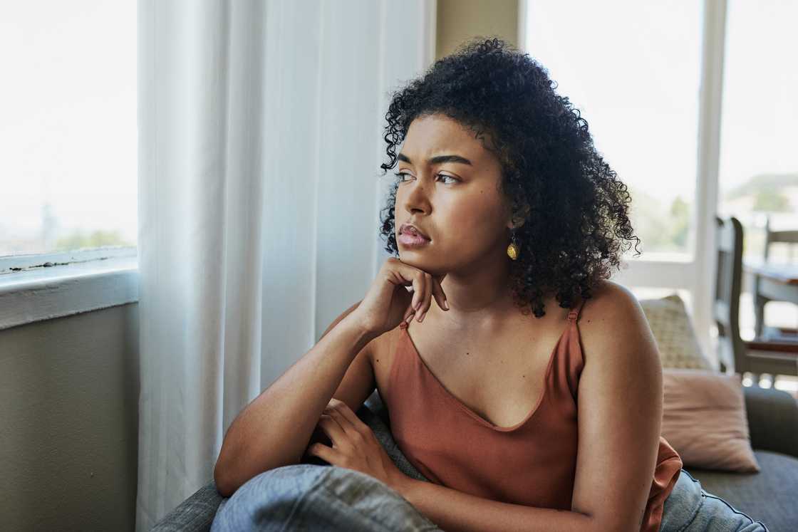 A young woman thinking while looking outside a window