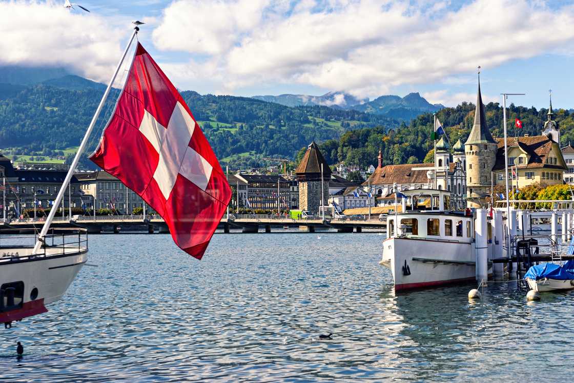 Swiss flag against background of the historic centre of Lucerne and Swiss Alps.