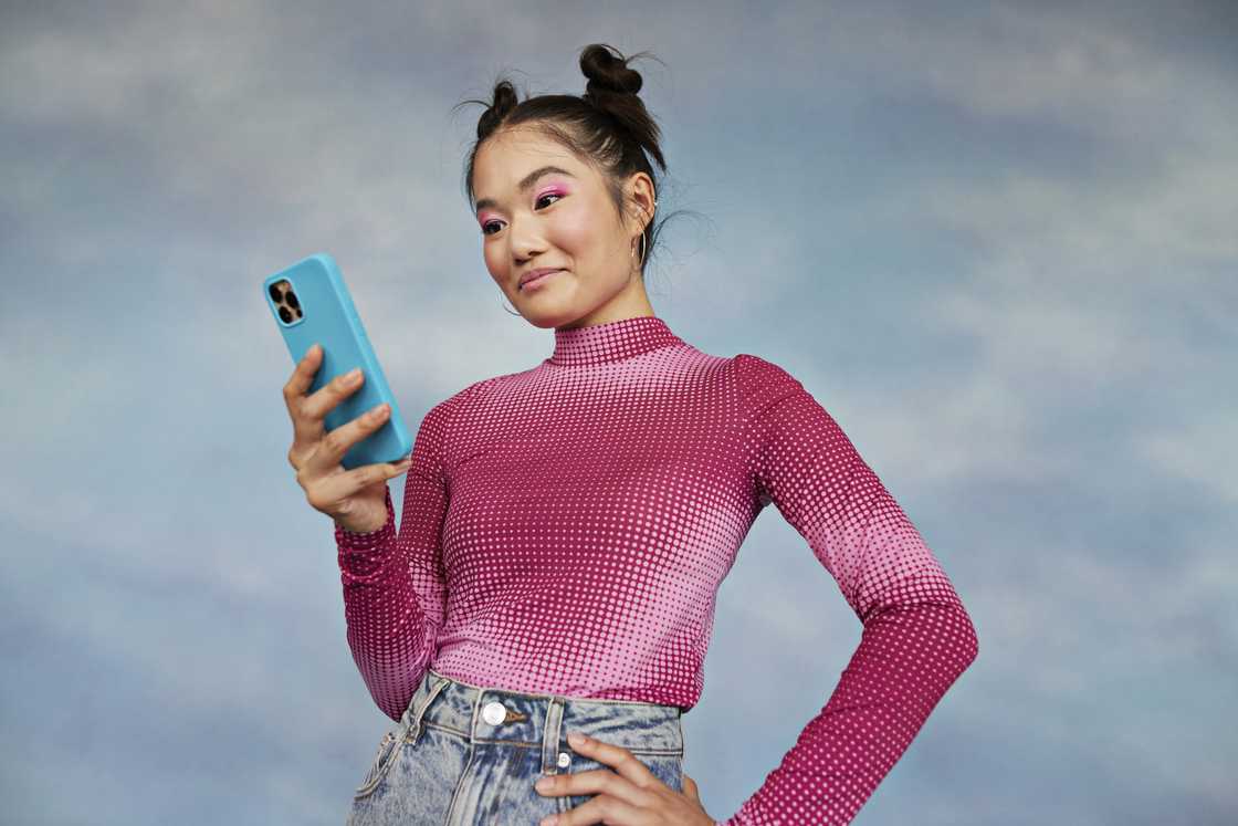 A woman smiles at her phone. A woman smiles at her phone.