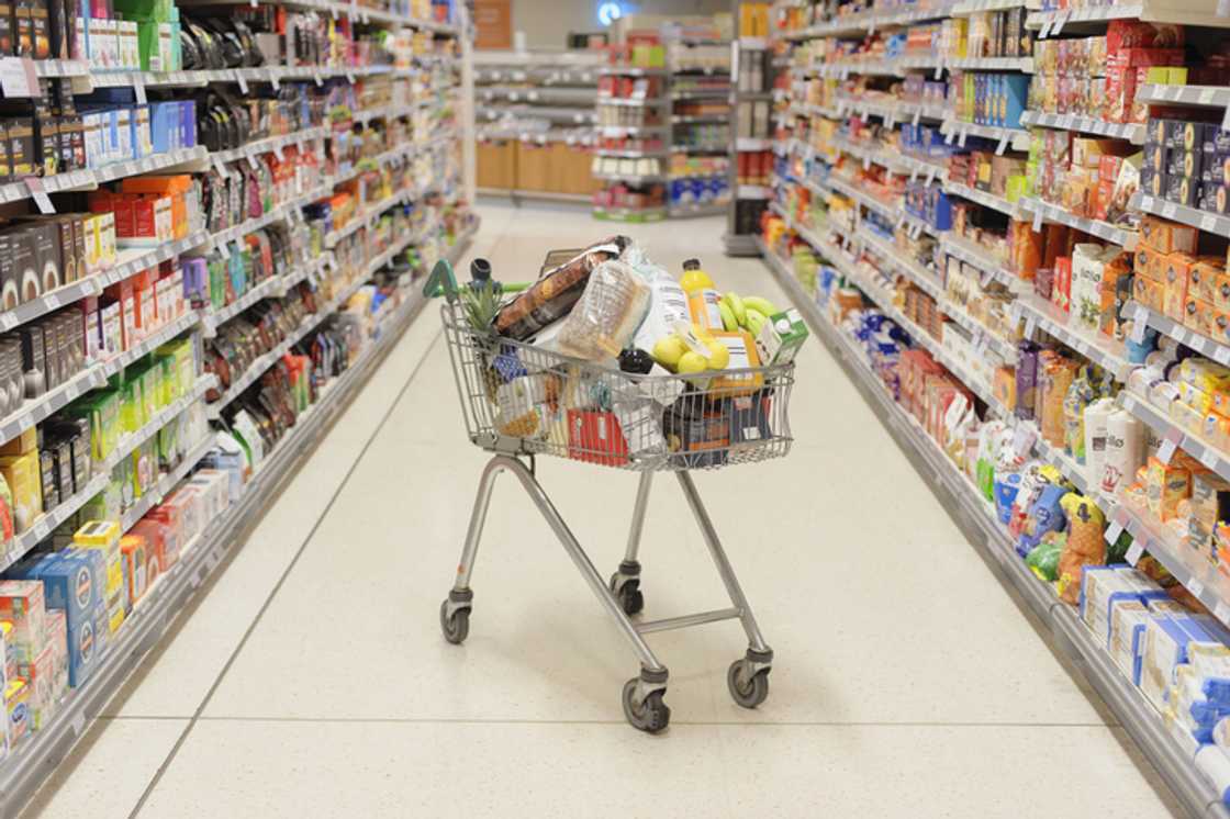 A trolley filled with loads of items in a shop was in an aisle. A trolley filled with loads of items in a shop was in an aisle.