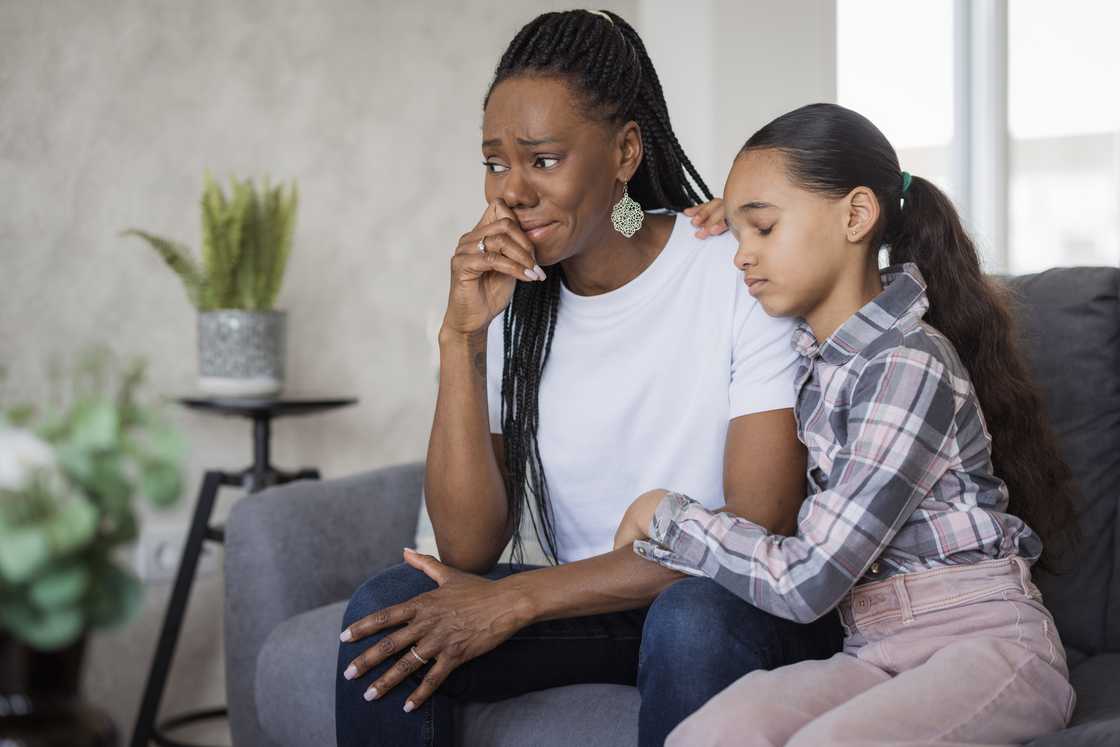 A worried young woman with a frightened child clinging to her shoulders
