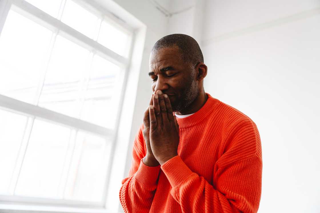 Mature man praying with hands clasped