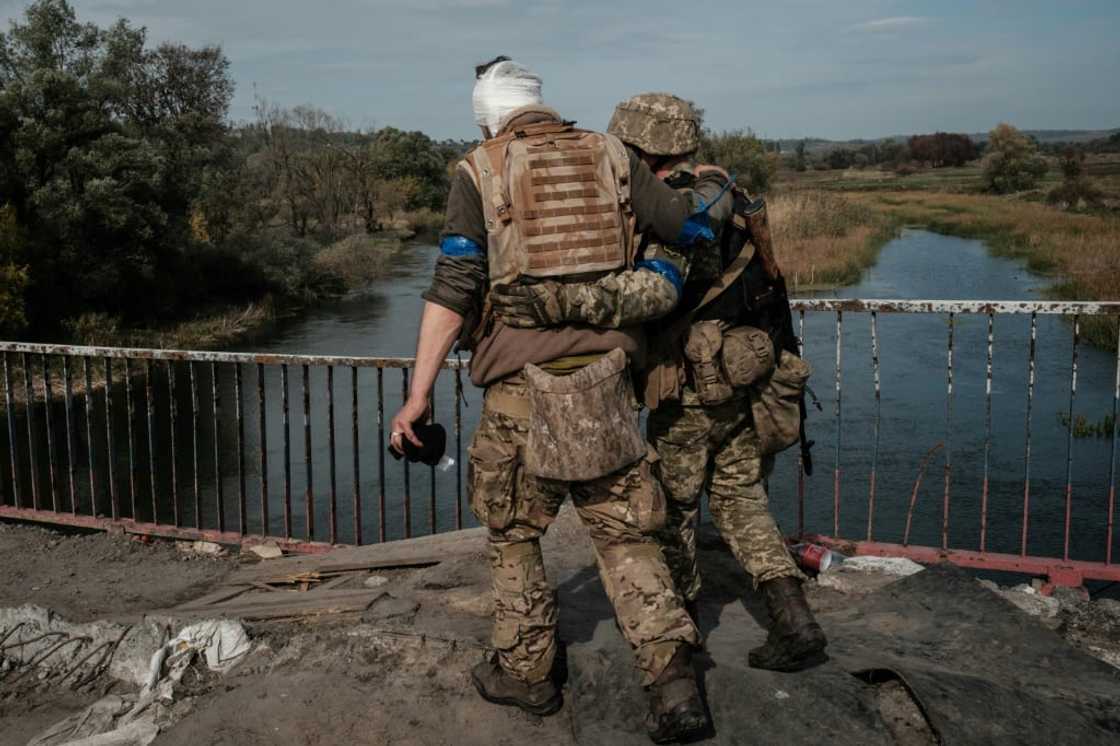 A wounded Ukrainian serviceman crosses a bridge in a recently retaken area near Kharkiv