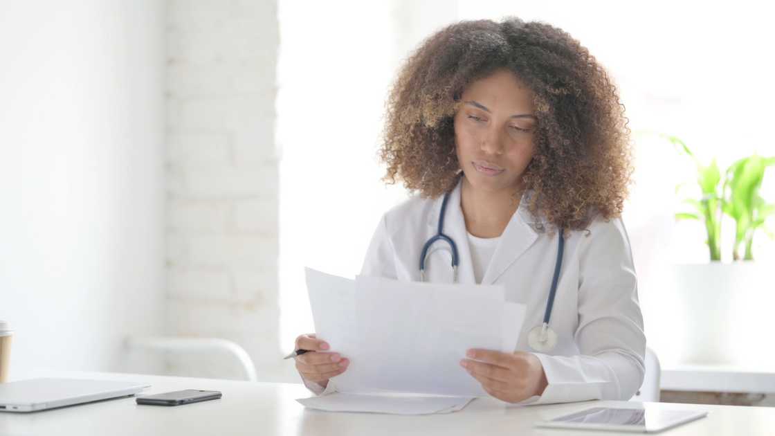 A young doctor reading documents while sitting in clinic