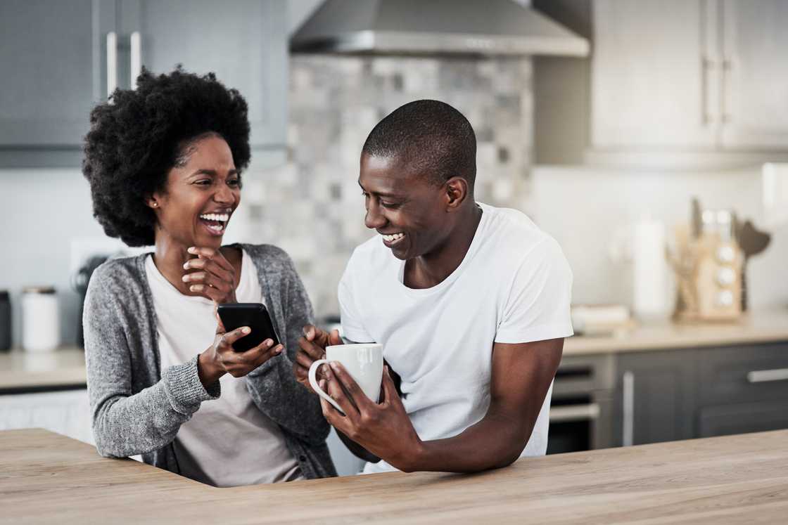 A couple laughing at what they saw on a phone.