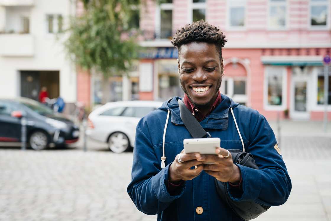 A man smiling at his phone. A man smiling at his phone.