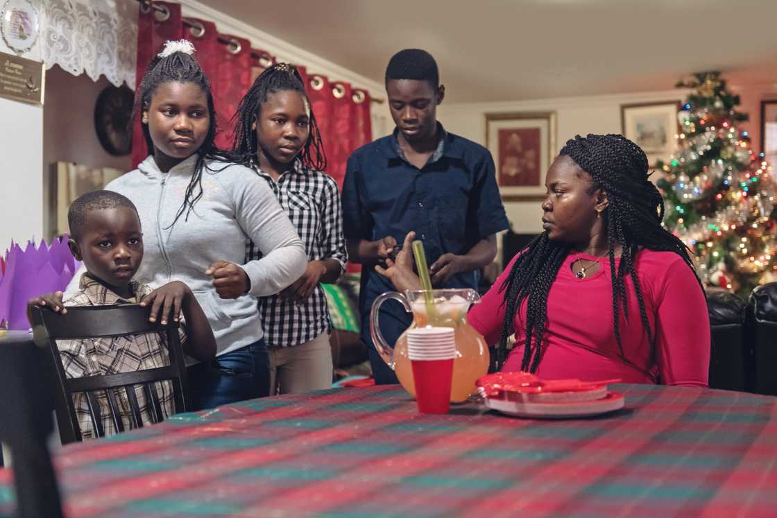 Group of people gather around a table in a warmly lit room.
