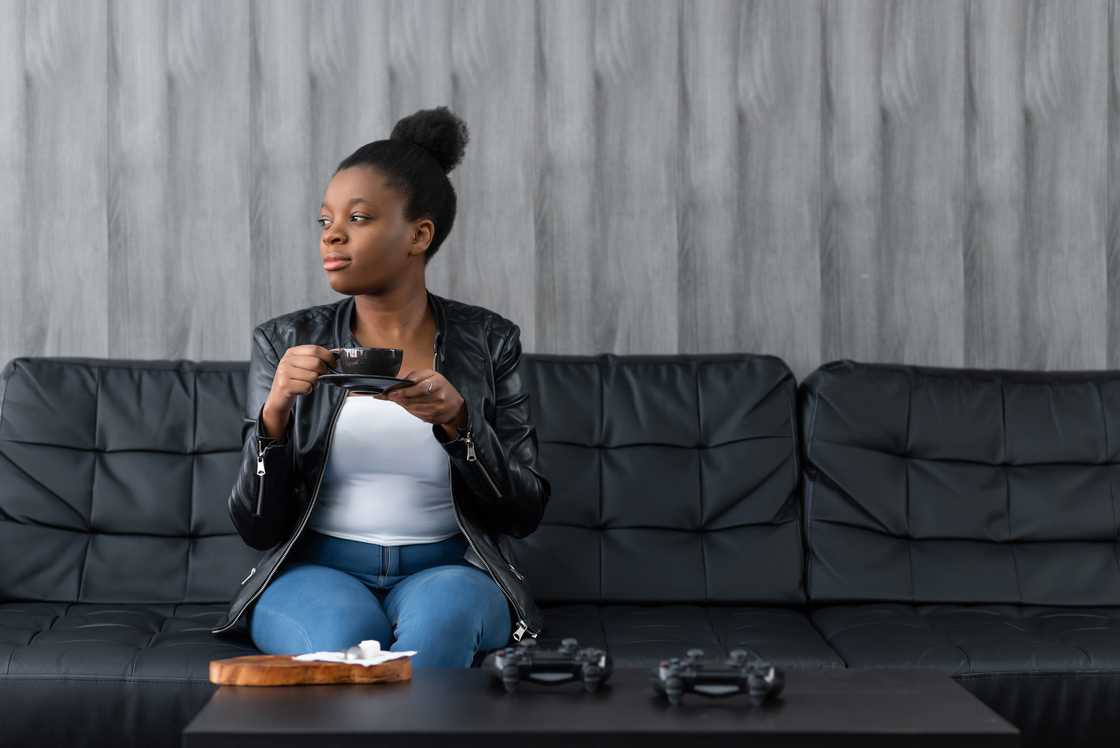 Young calm black woman relaxing sitting on black sofa Young calm black woman relaxing sitting on black sofa