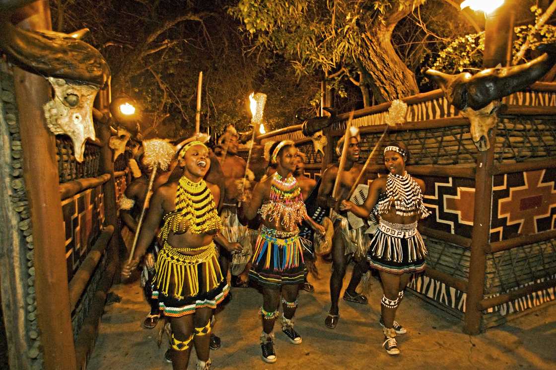 Zulu women dancing in costume of a young Zulu maiden. The entire outfit is made of beads. This costume is worn during festivals or dancing ceremonies. Lesedi Cultural Village near Johannesburg South Africa - stock photo Zulu women dancing in costume of a young Zulu maiden. The entire outfit is made of beads. This costume is worn during festivals or dancing ceremonies. Lesedi Cultural Village near Johannesburg South Africa - stock photo