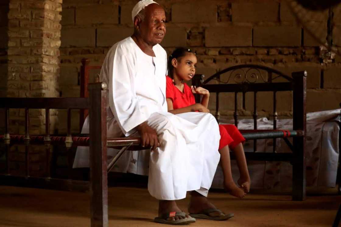 Nafisa, 8, who is unable to walk, is pictured sitting next to her father in the village of Banat Nafisa, 8, who is unable to walk, is pictured sitting next to her father in the village of Banat