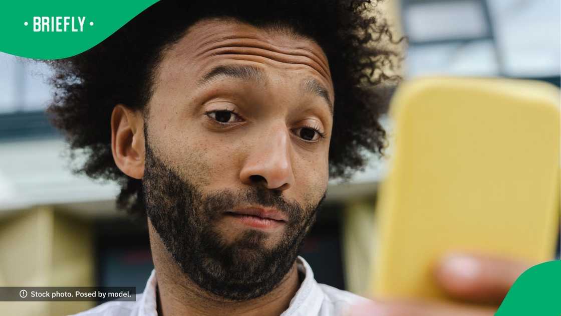 A man looking at his phone with raised eyebrows. A man looking at his phone with raised eyebrows.