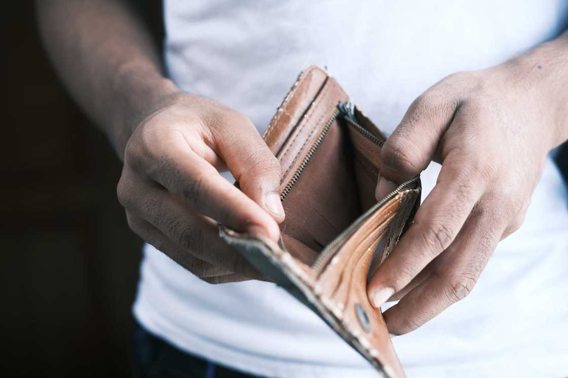 A person holds an empty wallet open with both hands. A person holds an empty wallet open with both hands.