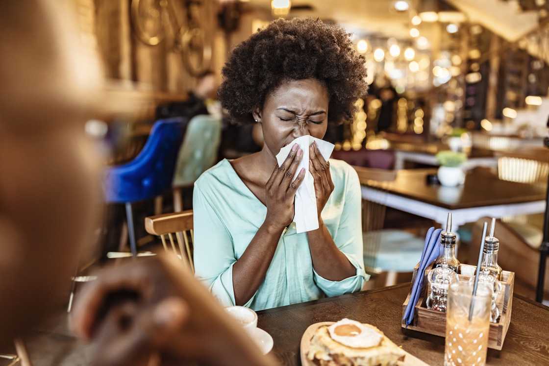 A lady uses a napkin to wipe her tears at a cafe A lady uses a napkin to wipe her tears at a cafe