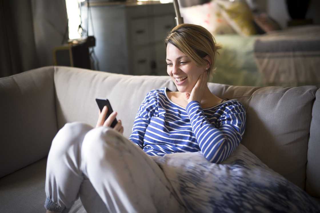 A woman smiling at her phone. A woman smiling at her phone.
