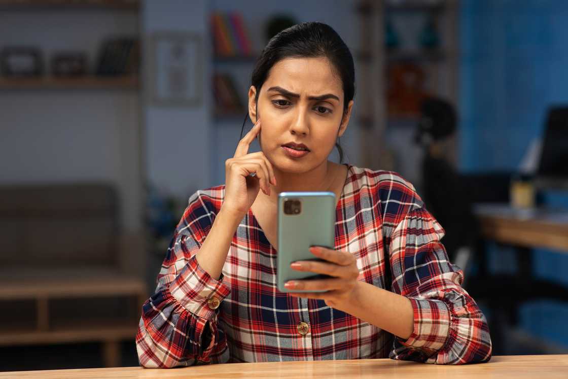 A confused woman looking at her phone.