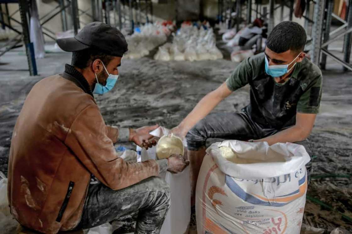Workers ration out flour during the distribution of humanitarian aid in Gaza City Workers ration out flour during the distribution of humanitarian aid in Gaza City