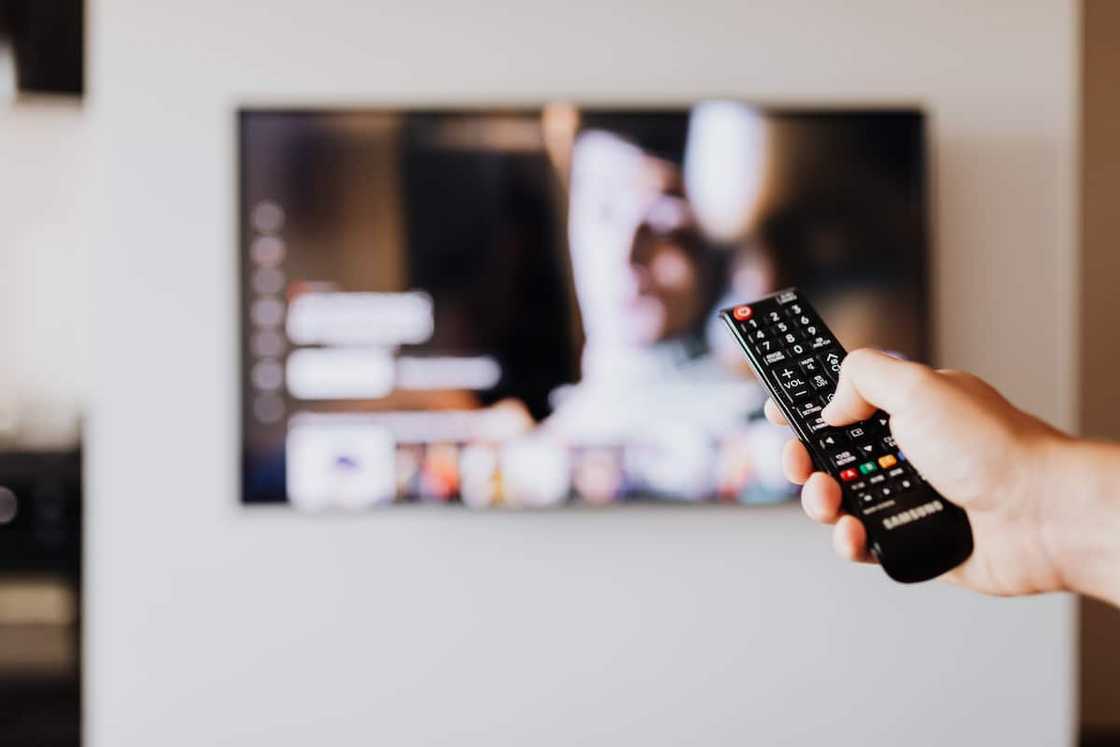 A person pressing the button of a remote control A person pressing the button of a remote control