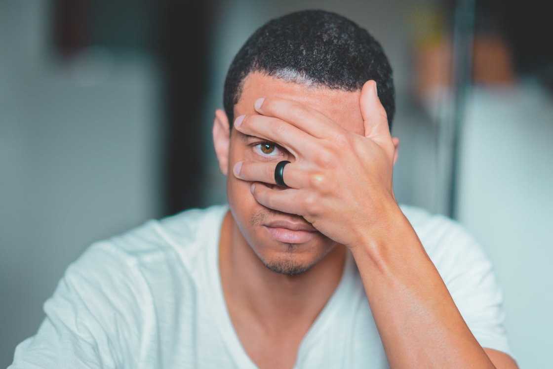 A man covers part of his face with his hand, looking stressed. A man covers part of his face with his hand, looking stressed.