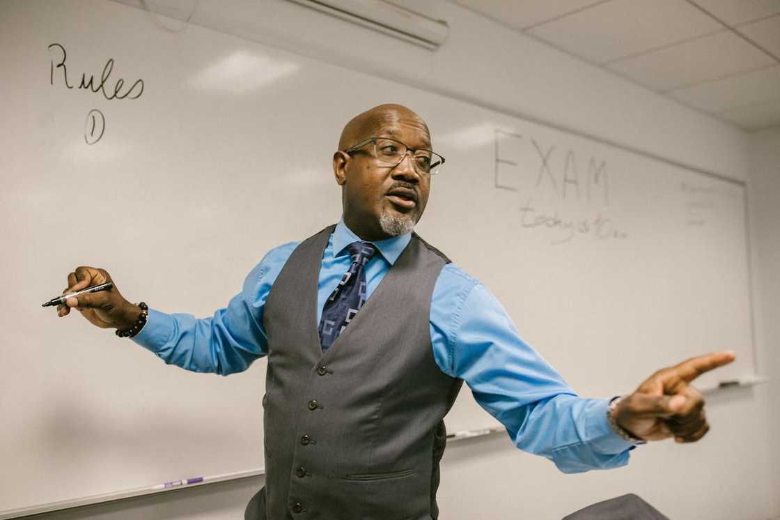 An instructor gestures while teaching in a classroom. An instructor gestures while teaching in a classroom.