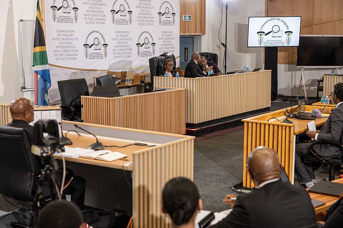 Justice Mbuyiseli Madlanga (Background 2nd R) and Advocate Sandile Khumalo SC (Background R)confer at the Madlanga Commission of Inquiry as Former minister of police Senzo Mchunu testifies in Pretoria on December 2, 2025 Justice Mbuyiseli Madlanga (Background 2nd R) and Advocate Sandile Khumalo SC (Background R)confer at the Madlanga Commission of Inquiry as Former minister of police Senzo Mchunu testifies in Pretoria on December 2, 2025