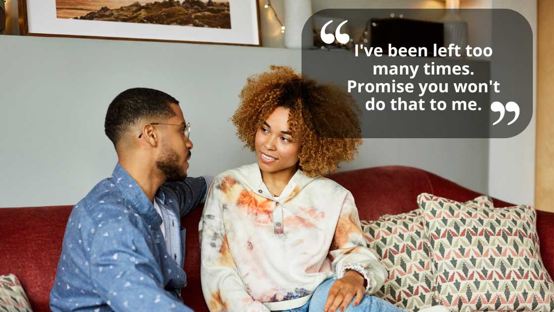 Girlfriend looking at boyfriend talking while sitting on sofa
