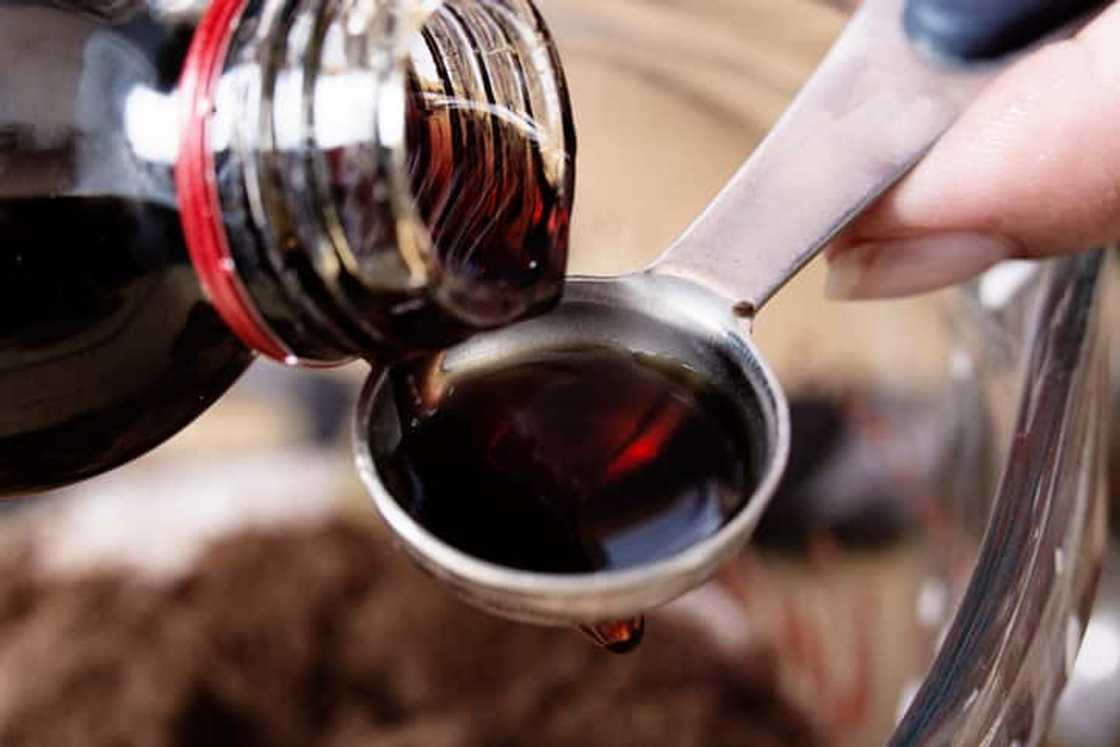 A bottle of vanilla extract poured into a teaspoon